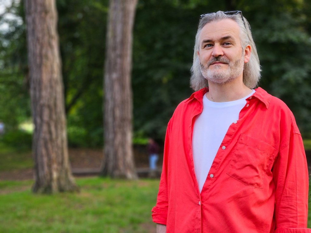 Samsung Galaxy S23 Ultra sample image, Outdoor Portrait of a man with shoulder length white hair and short beard wearing a white t-shirt and red shirt over it